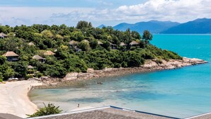 Ein Küstenort mit reetgedeckten Hütten, einem Sandstrand und klarem türkisfarbenem Wasser.