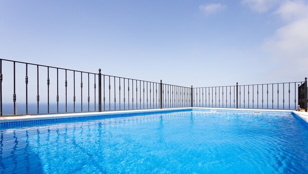 A clear blue pool with a black metal fence and a clear sky in the background. - Finca Vinco with heateble Pool (Alcalá)