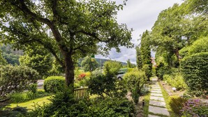 Un sentier de jardin bordé d’une végétation luxuriante et d’arbres.
