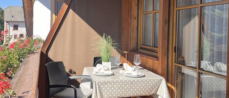 A dining area with a table set for two, a chair, and a potted plant.