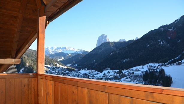 Ein Holzbalkon mit Blick auf eine verschneite Berglandschaft.
