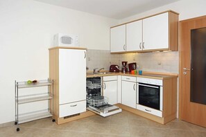 Uma cozinha compacta com armários brancos, micro-ondas, lava-louças e cafeteira.