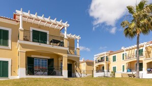 A two-story building with balconies, a covered entrance, and a palm tree in the foreground. - Beautiful apartment in a quiet location with sea views  (Porches - Alporchinhos)
