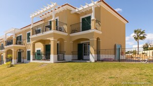 A multi-story building with balconies, a covered patio, and a well-maintained lawn. - Beautiful apartment in a quiet location with sea views  (Porches - Alporchinhos)
