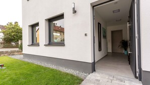 Un bâtiment moderne à la façade épurée, doté d’une pelouse bien entretenue et d’une entrée bien visible, avec une porte et des marches.