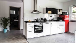 Une cuisine moderne avec des armoires blanches, une hotte de cuisinière en acier inoxydable et un réfrigérateur rouge.