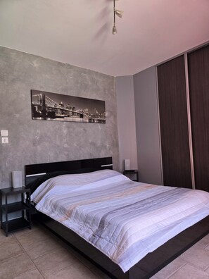 Une chambre à coucher comprenant un lit, une table de chevet, une commode, un tableau accroché au mur et une armoire.