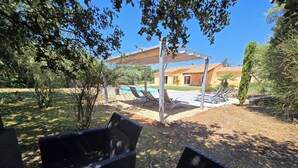 A patio area with wicker furniture, a pool, and a building with a tiled roof.