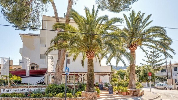 A restaurant with a sign 'Restaurante La Calama' and palm trees in the foreground.