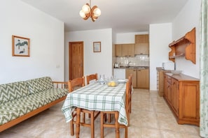 A dining area with a table set for four, a wooden cabinet, and a kitchen in the background. - Holiday Apartment "La Cabanya 2A" with Wi-Fi, balcony, terrace and shared pool (CANYAMEL)