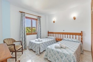 A bedroom with two beds, a chair, a table, and a window with curtains. - Holiday Apartment "La Cabanya 2A" with Wi-Fi, balcony, terrace and shared pool (CANYAMEL)