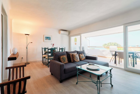 A modern living room with a sofa, coffee table, and a dining area with a table and chairs.