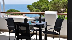 Ein Balkon mit Tisch und Stühlen mit Blick auf das Meer.