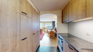 Una cucina moderna con mobili in legno, un'area pranzo con tavolo e sedie, e vista su un balcone.