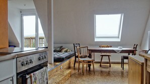 Eine kompakte Küche mit Einbauofen, einem Esstisch mit Stühlen und einem großen Fenster für natürliches Licht.