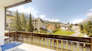 A balcony with a view of a residential area, including houses and mountains.