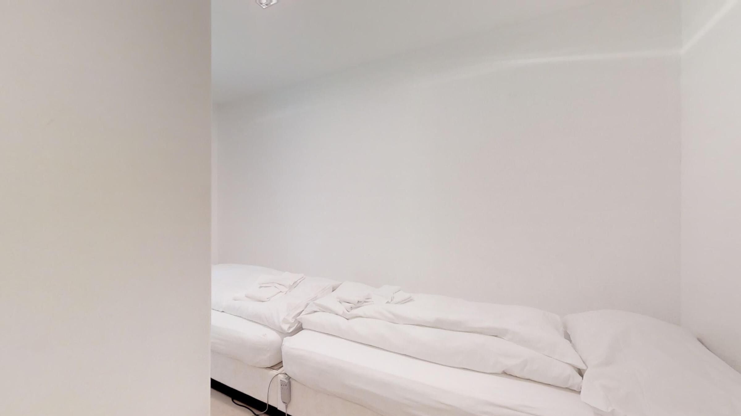 Une petite chambre blanche avec un lit simple, au design épuré et minimaliste.