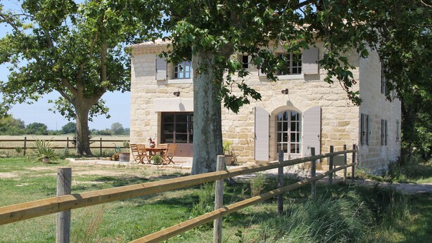 A stone building with a wooden fence, a table, and chairs outside. - Le Mazet Jean. Camargue Bed and Breakfast (kindling) (Le Cailar)