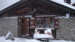 Una cabaña de madera con techo y ventanas cubiertas de nieve, rodeada por la nieve.