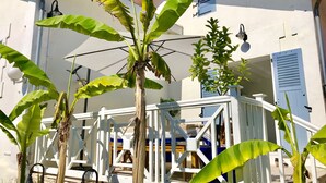 Un edificio blanco con un balcón, una campana y una planta de plátano.