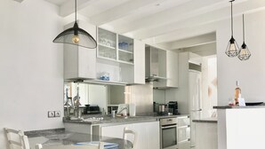 Una cocina moderna con armarios blancos, encimera de granito y comedor con sillas blancas.