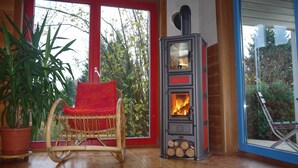 Un intérieur en bois avec un fauteuil à bascule, un poêle à bois et une grande fenêtre.