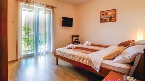 A hotel room with a bed, a chair, a table with a book and a vase, a painting on the wall, and a TV on the wall. - Amazing home in Bast with house a panoramic view (Bast)