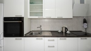 A modern kitchen with white cabinets, a stainless steel sink, a built-in oven, and a kettle on the counter. - Amazing home in Bast with house a panoramic view (Bast)