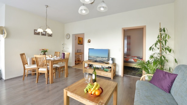 Een woonkamer met een eethoek, een televisie en een plant.