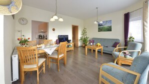 Een gezellige woonkamer met een eethoek, houten meubels en uitzicht op de keuken.