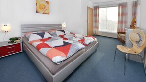 Een moderne hotelkamer met een groot bed, een nachtkastje, een stoel en een raam met gordijnen.