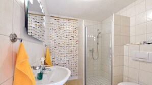 Een badkamer met een wastafel, spiegel, toilet en douche.