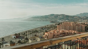 Un paisaje urbano costero con playa, palmeras y edificios.