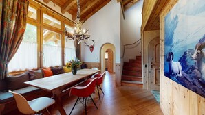 A dining area with a wooden table, red chairs, and a chandelier.