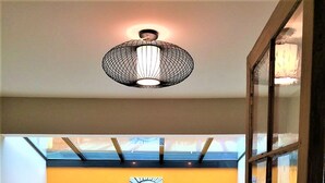 Un salon moderne avec un canapé bleu, des coussins à motifs, une œuvre d’art murale en forme de spirale et un luminaire au plafond original.