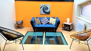 Un salon moderne avec un canapé bleu, des coussins à motifs et une table basse en verre.