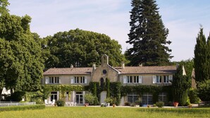 A two-story building with a symmetrical facade, large windows, and a central arched entrance. - La Petite Maison, 14 p., at the beautiful “Domaine de Vincenti » (Domaine de Vincenti Divajeu)