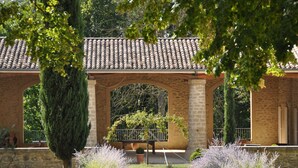 A covered outdoor area with stone arches, potted plants, and a gravel path. - La Petite Maison, 14 p., at the beautiful “Domaine de Vincenti » (Domaine de Vincenti Divajeu)