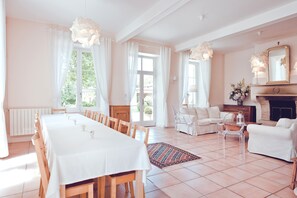 Tilava huone, jossa on ruokapöytä kuudelle, takka ja viihtyisä oleskelualue, jossa on sohva ja nojatuoleja.