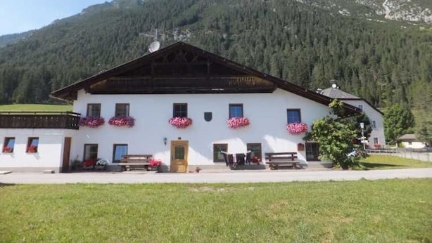 Un bâtiment blanc avec un toit en pente, de nombreuses fenêtres et des jardinières sur la façade.