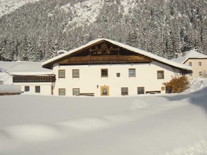 Ein Gebäude mit einem geneigten Dach, mehreren Fenstern und einer verschneiten Landschaft.