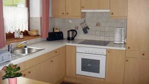 Une cuisine compacte avec des meubles en bois, un four encastré, un évier et une machine à café.