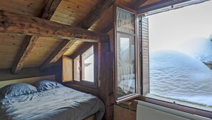 Una habitación de cabaña de madera con una cama, un ventanal y vistas a un paisaje nevado.