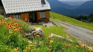 Una casa con techo inclinado, base de piedra y porche delantero.