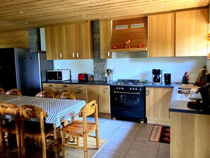 Una cocina con armarios de madera, microondas, estufa y comedor con mesa y sillas.