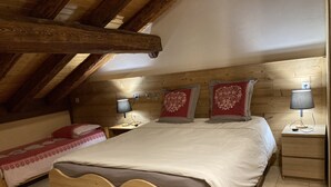 Una camera da letto accogliente con un letto in legno, due comodini con lampade e un soffitto a falde con travi a vista.
