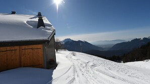 Una montaña nevada con una cabaña de madera y cielo despejado.