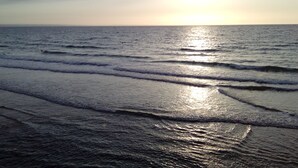 Une plage avec des vagues et le soleil qui se reflète sur l’eau.