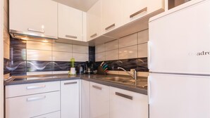 Une cuisine moderne avec des armoires blanches, un évier en acier inoxydable et un dosseret noir.