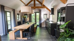Una cocina moderna con una mesa de comedor de madera, armarios negros y un ventanal grande.